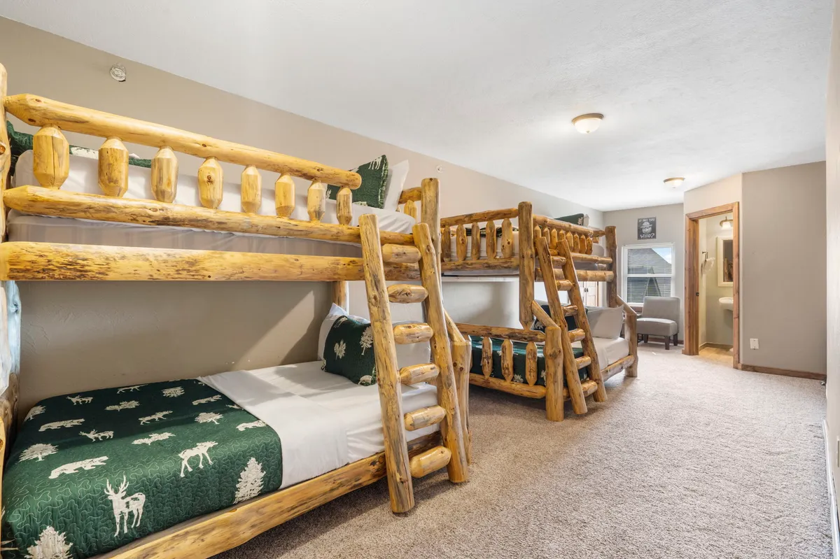 A playful and inviting bunkroom with wooden bunk beds, textured bedding, and welcoming wood accents. The space is designed for both relaxation and fun, making it ideal for children's sleepovers or family bonding.