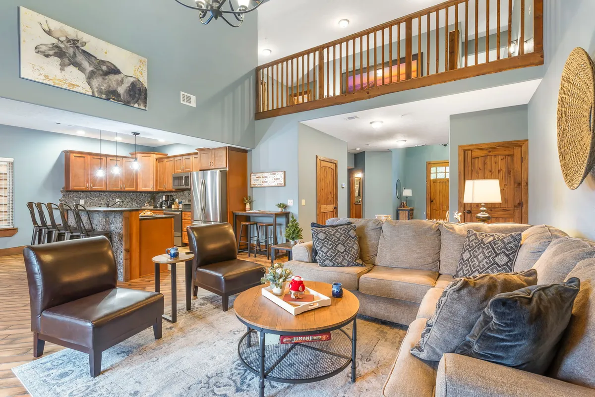 The hero image showcases a spacious, beautifully decorated living area with a cozy sofa, a stylish coffee table, and an inviting kitchen in the background. The scene radiates warmth and comfort, perfect for gathering with friends or family to relax, share stories by the fireplace, or enjoy a meal together.
