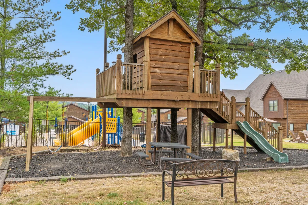 A delightful outdoor playground with a whimsical treehouse, a winding slide, classic playground equipment, and a bench nestled among trees. Children are seen playing and families are gathering, evoking a sense of adventure and community for all ages.